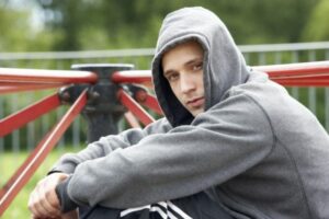 Young homeless young-man-sitting-in-playground-shutterstock_35037541-600x400